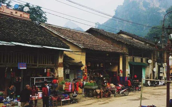 Market street in a village on the Sapa to Ha Giang Loop, showcasing local shops and traditional architecture.