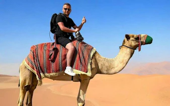Camel ride in Abu Dhabi desert during private 4x4 safari tour.