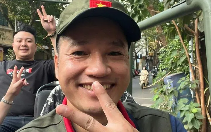 Tourists enjoying a Hanoi Jeep city tour with peace signs, surrounded by greenery.