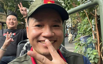 Tourists enjoying a Hanoi Jeep city tour with peace signs, surrounded by greenery.