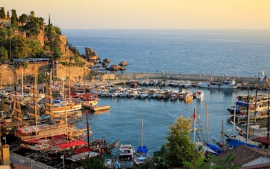 Antalya harbor with boats and cliffs during sunset on self-guided walking tour.