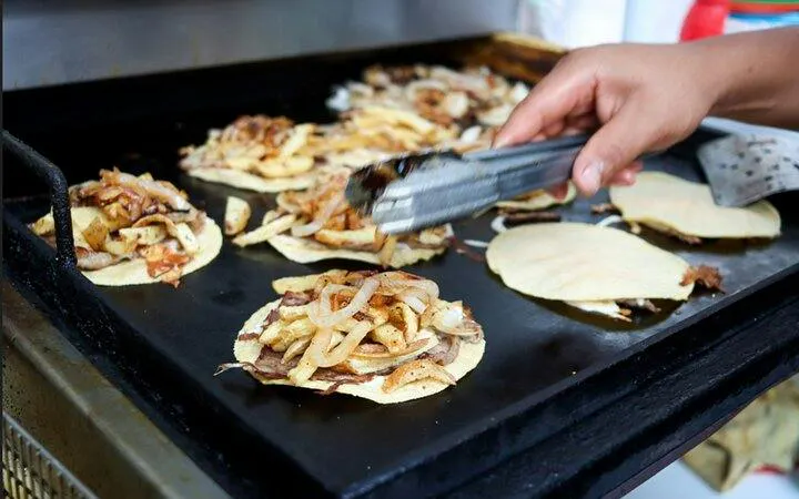 Tacos being prepared on a griddle in Mexico City during a bike tour.
