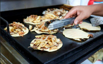 Tacos being prepared on a griddle in Mexico City during a bike tour.