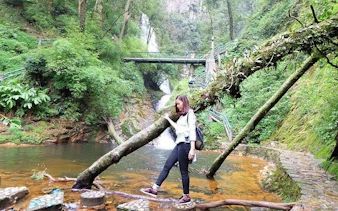 Visitor exploring Love Waterfall area in Sapa with lush greenery and a scenic bridge.