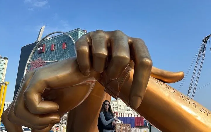 Gangnam Style statue in Seoul with a visitor standing beneath.