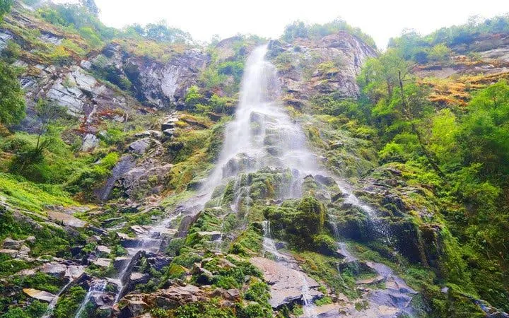 Waterfall cascading down rocky cliff surrounded by lush greenery in Sapa, Vietnam.