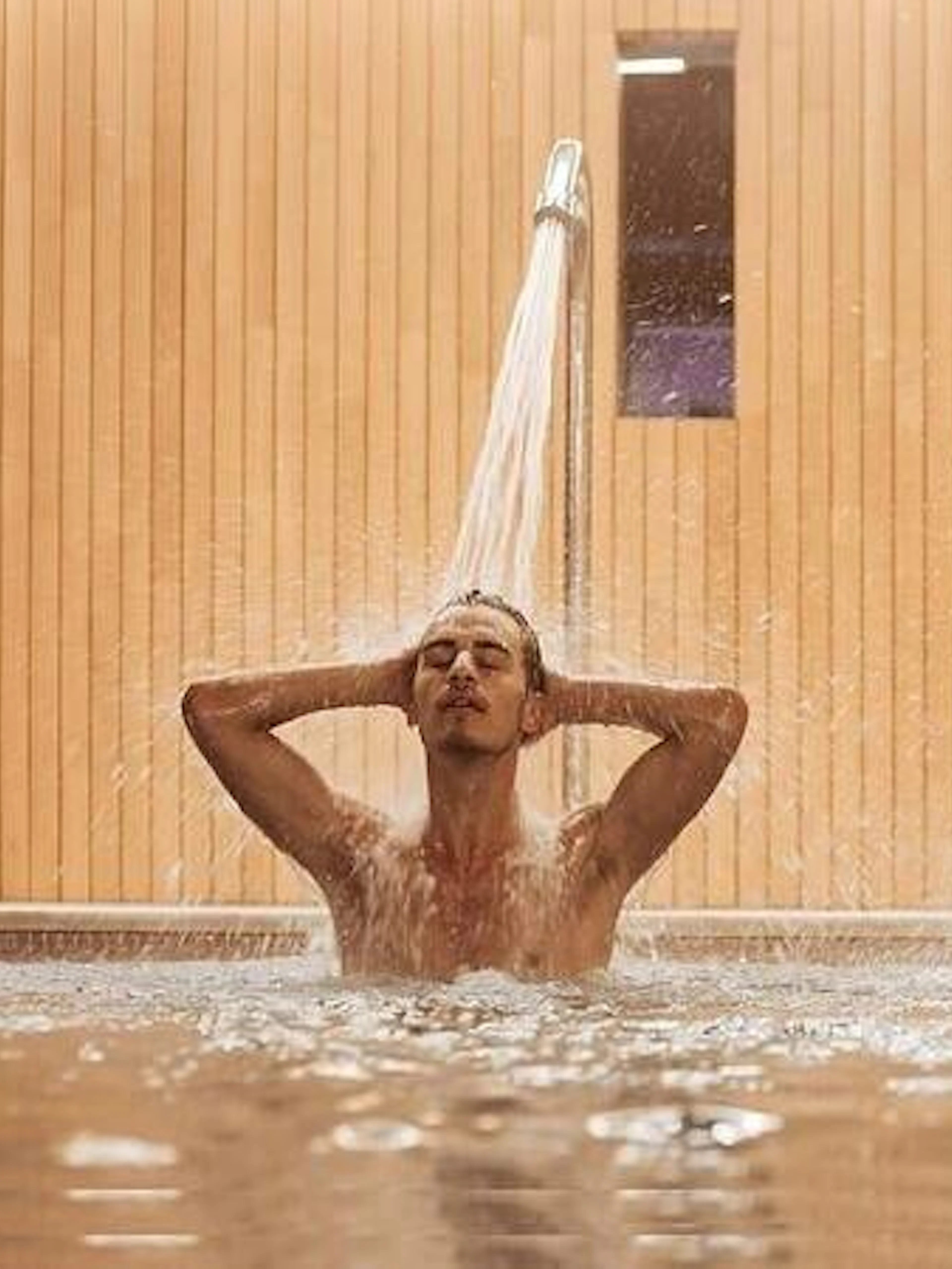 Couple enjoying water jets in a traditional Moroccan hammam, Marrakesh.