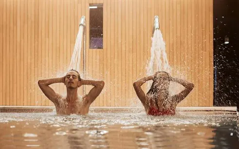 Couple enjoying water jets in a traditional Moroccan hammam, Marrakesh.