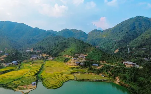 Sapa rice terraces and village near a lake with mountains in the background.