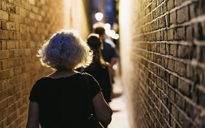 Walking through narrow alley on York haunted tour with historic stories.
