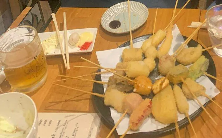 Skewered tempura dishes and beer on a table during Shinjuku food tour in Tokyo.