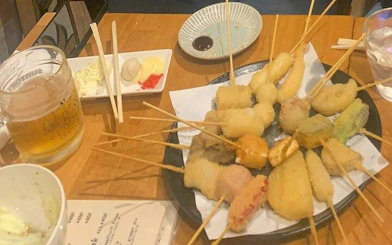 Skewered tempura dishes and beer on a table during Shinjuku food tour in Tokyo.