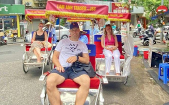 Cyclo tour in Hanoi's Old Quarter with tourists seated, exploring Train Street.
