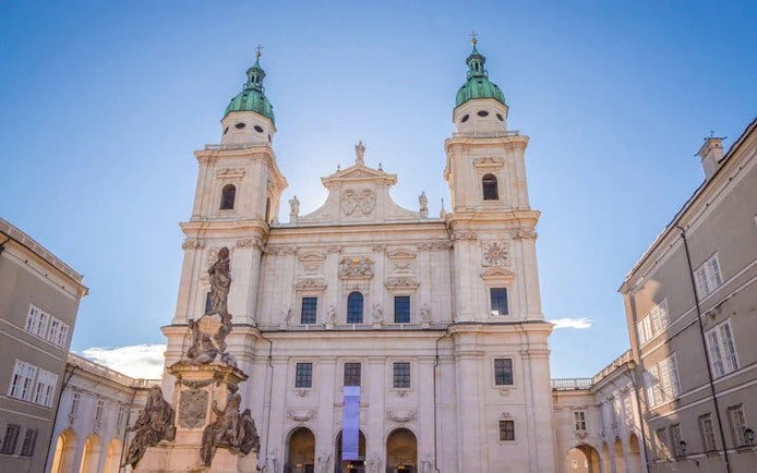 Salzburg Cathedral facade with statue, part of self-guided walking tour on mobile app.