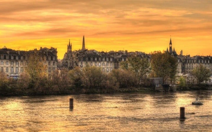 Bordeaux skyline at sunset viewed from the river, featuring historic architecture.