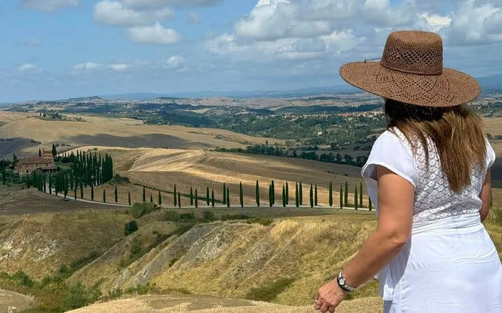 Woman overlooking Tuscan landscape with cypress trees near Siena, Italy.