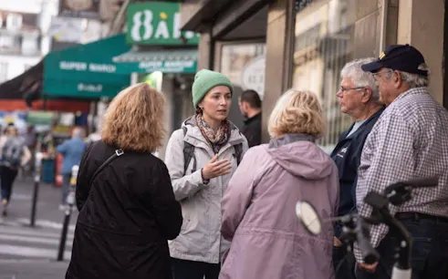 Tour guide leading a group in Montmartre, Paris, near local shops.