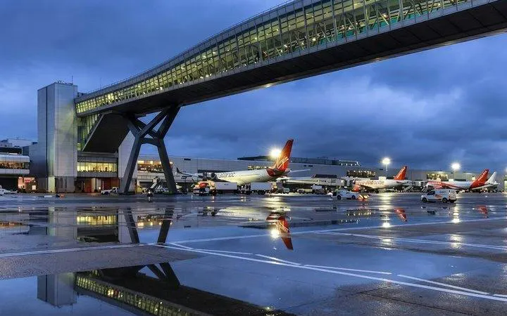 Gatwick Airport runway with planes and terminal bridge at dusk, London transfer service.