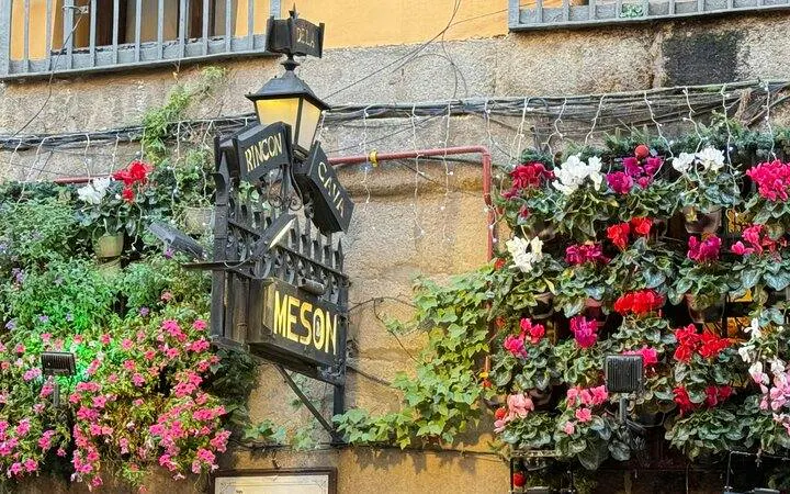 Historic Madrid tavern sign with colorful flowers in Old Town.