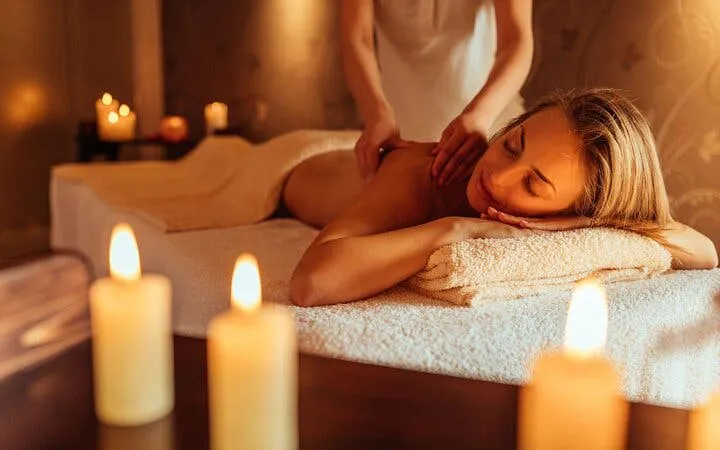 Person receiving a massage in a candlelit spa setting, part of Turkish Bath Experience in Sharm El Sheikh.