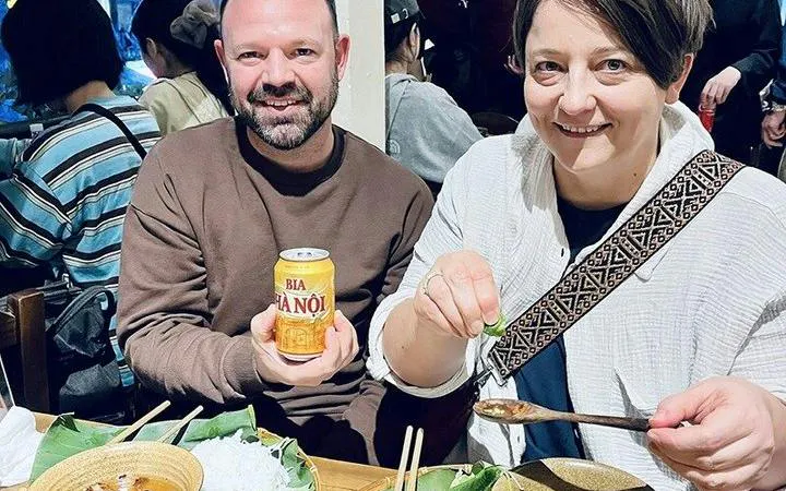 Tourists enjoying street food and Hanoi beer during a cyclo tour in Hanoi's Old Quarter.