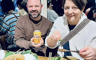 Tourists enjoying street food and Hanoi beer during a cyclo tour in Hanoi's Old Quarter.