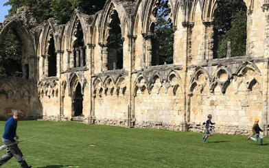 Ruins of St. Mary's Abbey in York with people playing on the grass during a Harry Potter walking tour.
