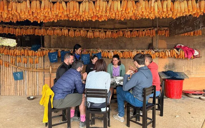 Tourists dining under corn displays during private car tour from Sapa to Mu Cang Chai rice terraces.