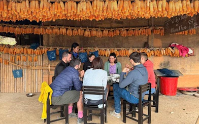 Tourists dining under corn displays during private car tour from Sapa to Mu Cang Chai rice terraces.