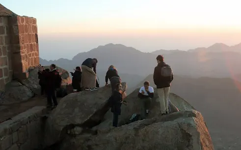 Group of hikers at sunrise on Moses Mountain near Saint Catherine Monastery, Sinai Peninsula.