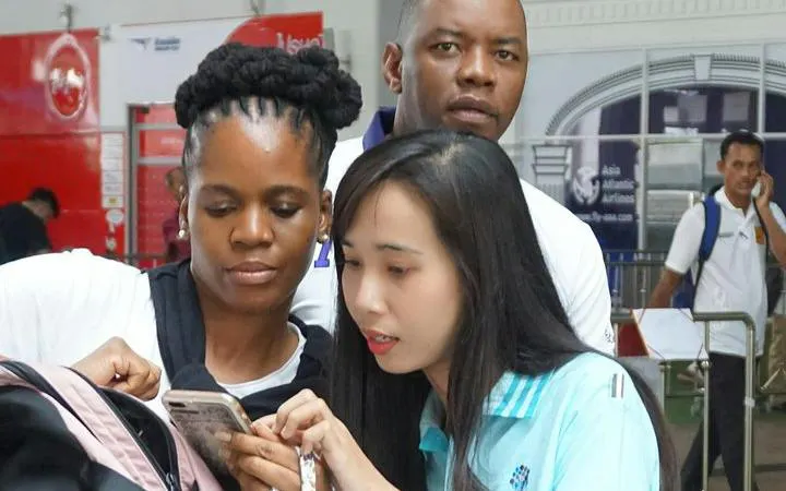 Phuket Airport arrival assistance with travelers checking phone for transfer details.
