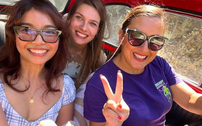 Three people smiling inside a vintage Fiat 500 during a Chianti and San Gimignano tour.