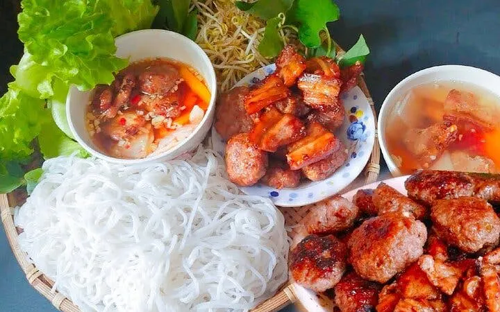 Bun Cha with grilled pork, noodles, and fresh greens in a Vietnamese cooking class setting.