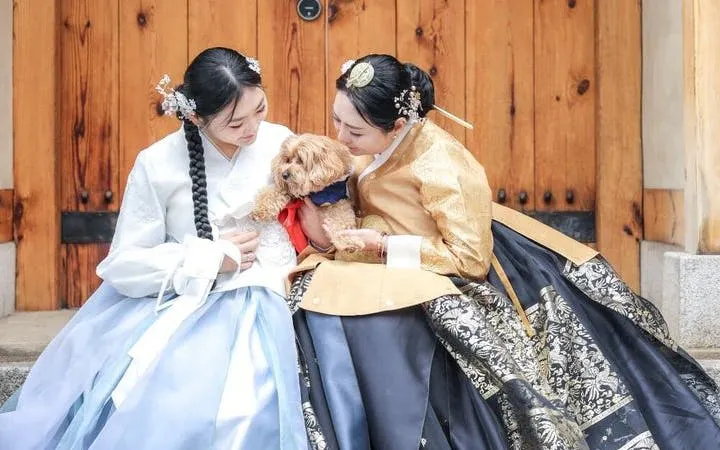 Women in traditional hanbok with a dog at Gyeongbokgung Palace, Seoul.