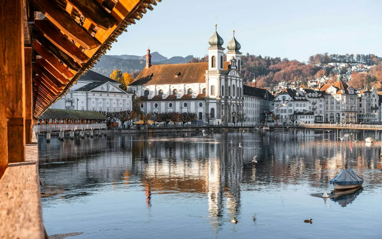 Chapel Bridge and Jesuit Church reflected in Reuss River, Lucerne Old Town.