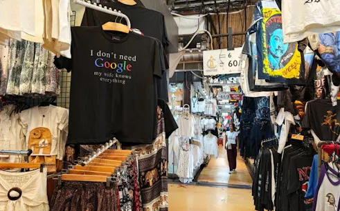 Chatuchak Market clothing stalls with graphic t-shirts and local fashion in Bangkok.