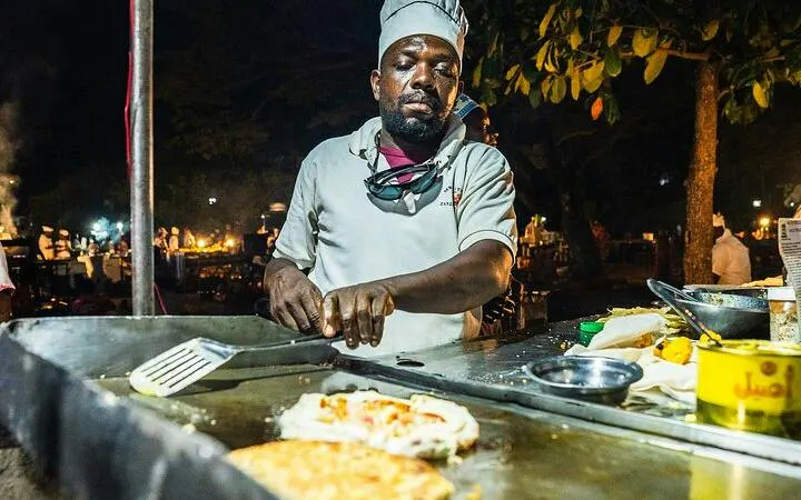 Chef cooking at Stone Town Zanzibar night food market during walking tour.