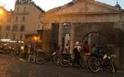 Bicyclists gather near an ancient Roman building during a night tour in Rome.
