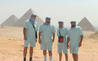 Tourists in front of Giza Pyramids, Egypt, wearing headscarves, part of guided tour with camel ride.