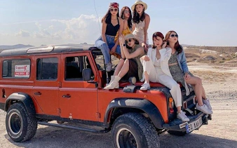 Cappadocia Jeep Safari with group on vehicle in rocky landscape.