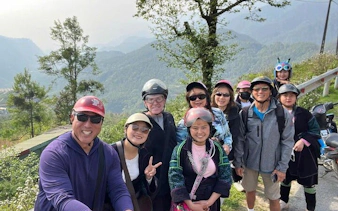 Group of tourists on a Sapa motorbike tour with rice fields and mountains in the background.