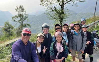 Group of tourists on a Sapa motorbike tour with rice fields and mountains in the background.