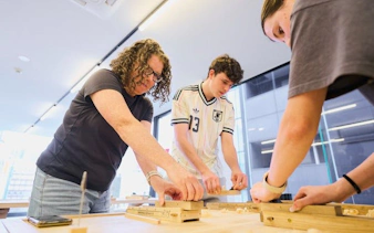 Participants crafting chopsticks at a Tokyo Shinjuku workshop, selecting wood and engraving kanji.