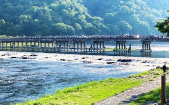 Togetsukyo Bridge over Katsura River in Arashiyama, Kyoto, surrounded by lush green hills.