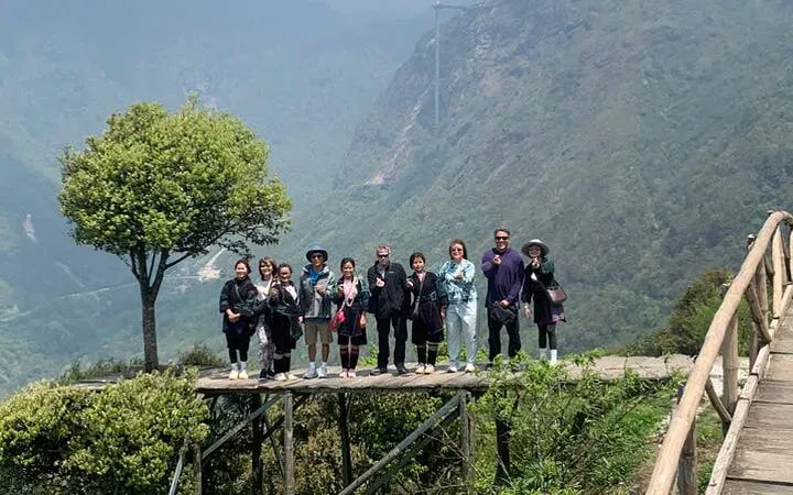 Group on a wooden platform overlooking Sapa's lush valleys during a guided motorbike tour.