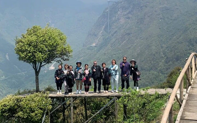 Group on a wooden platform overlooking Sapa's lush valleys during a guided motorbike tour.
