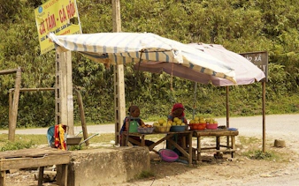 Market stall with fruit vendors under a canopy on Bac Ha Market day trip route from Sapa.