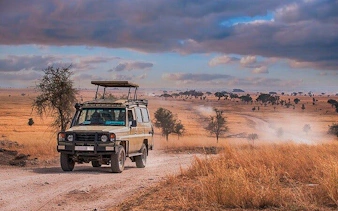 Safari jeep on dirt road in Tanzania's Selous Game Reserve.