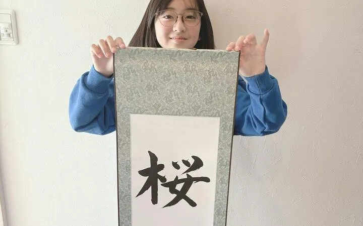 Local instructor holding Japanese calligraphy scroll in Yamanashi class.