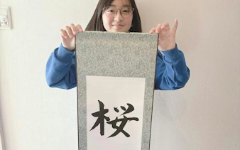 Local instructor holding Japanese calligraphy scroll in Yamanashi class.